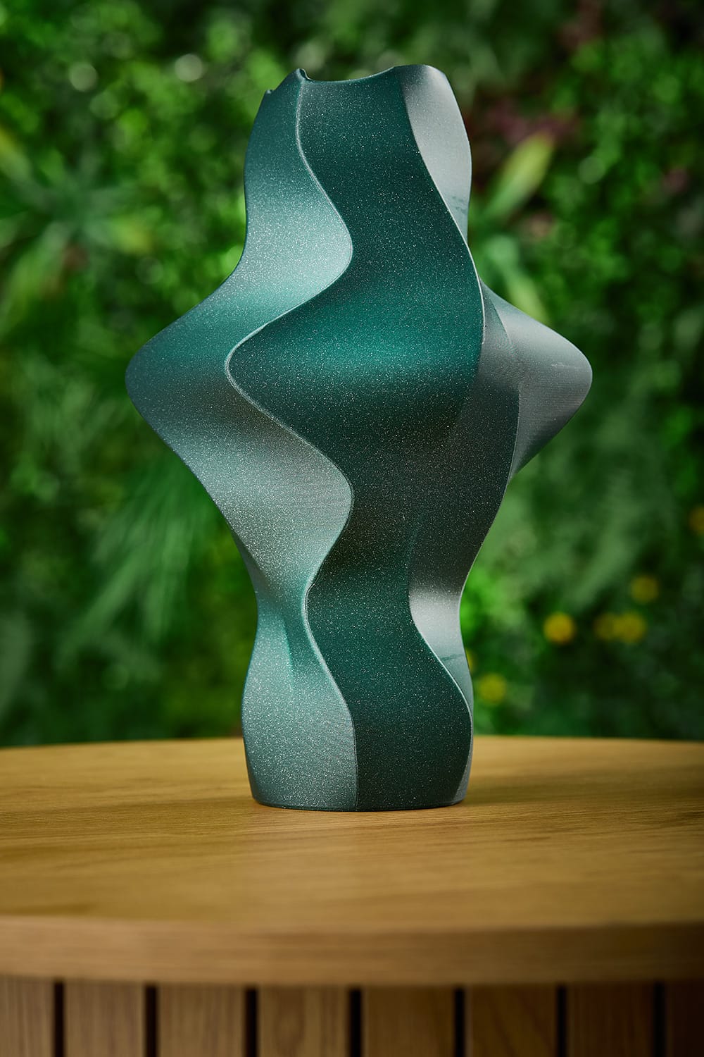 Fivi vase in green displayed against a green foliage backdrop