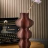 Selini vase in brown styled with a flower beside a vintage typewriter