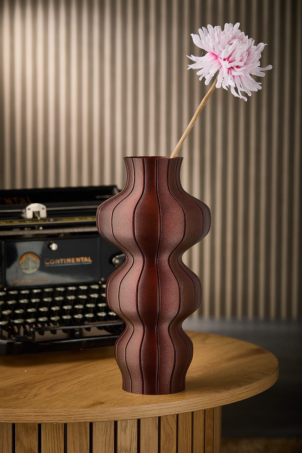 Selini vase in brown styled with a flower beside a vintage typewriter